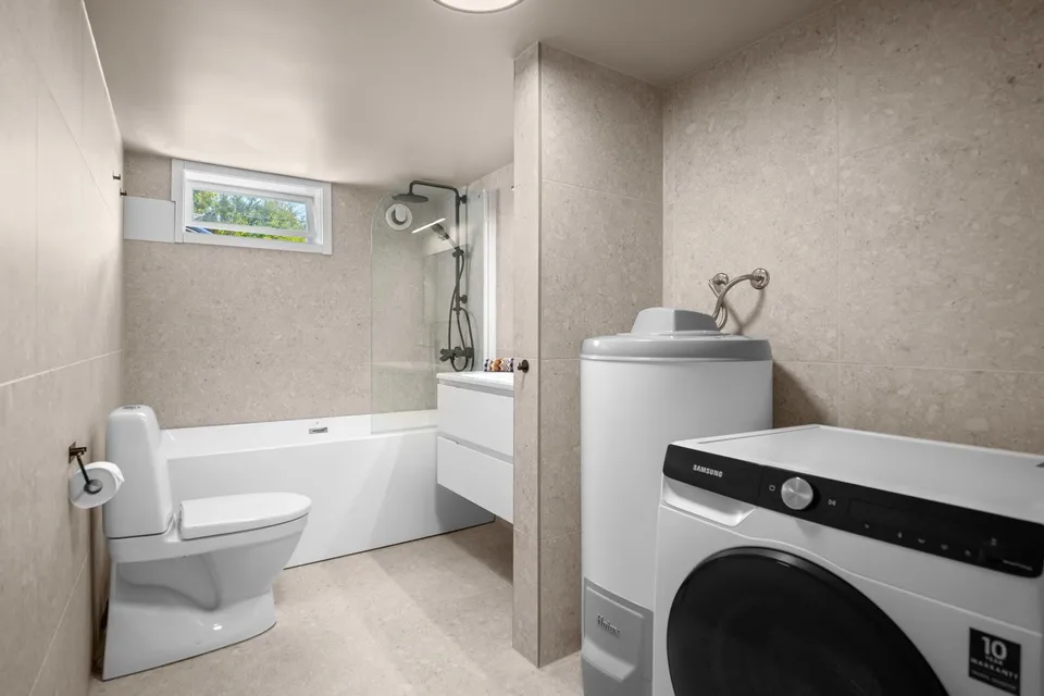 Renovated basement room with bathtub and washing machine