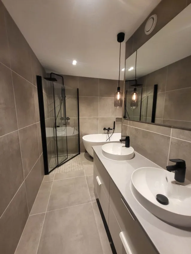 Bathroom with twin basins, grey tiles and glass shower screens