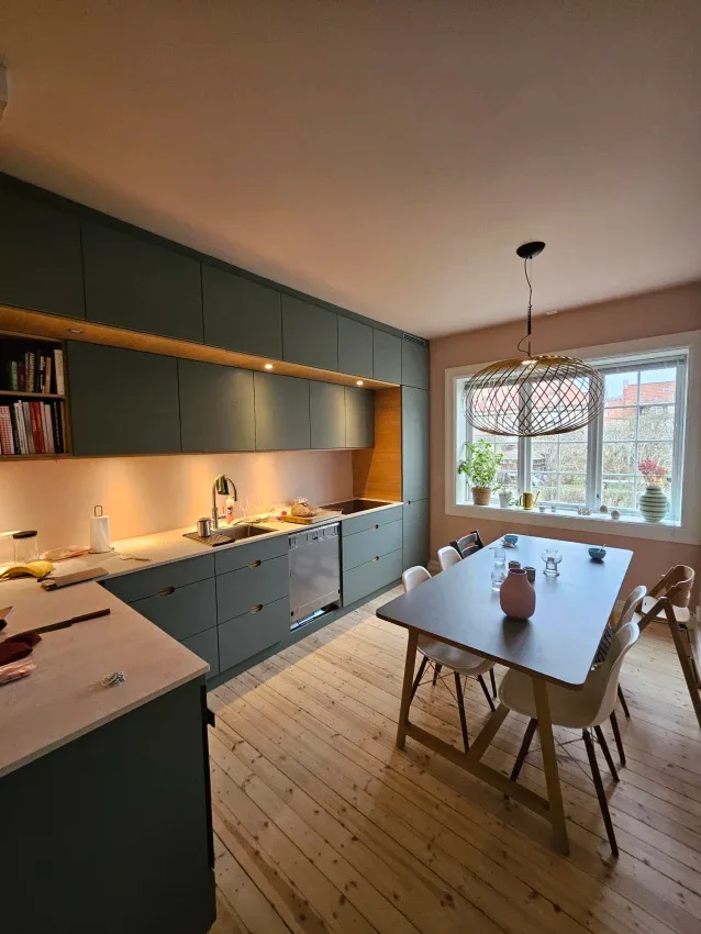Kitchen with green cabinets and a dining table by the window